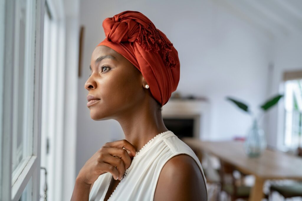 Thoughtful african woman thinking while looking outside the window